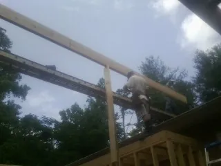 Carpenter setting a ridge beam over a new addition frame — Ice Dam Removal by Roofing Brothers in Grand Bay