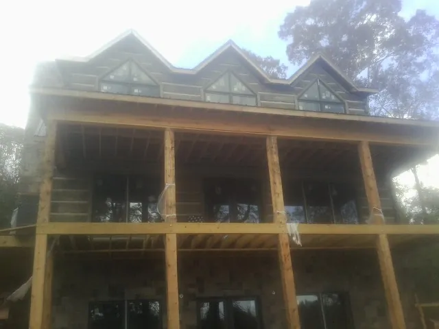 Dormers and porch framing on a large log home under construction — Roof Coating work by our crew in Grand Bay