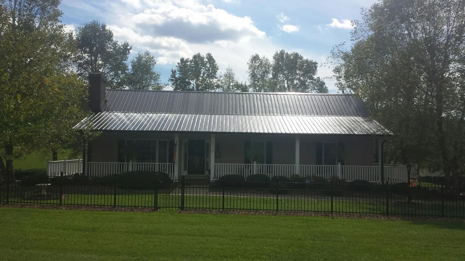 Gray metal roof on a brick ranch with a full width front porch — Gutter Guard Installation work by our crew in Grand Bay