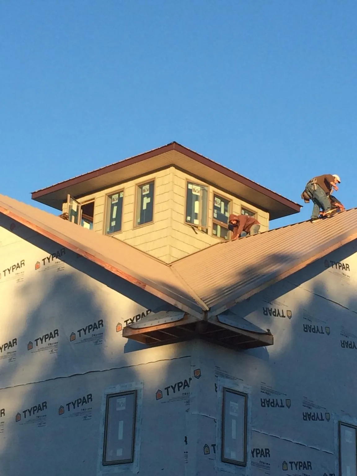 Roofers working around a rooftop cupola on a new metal roof at sunset — Roof Waterproofing in Grand Bay by Roofing Brothers
